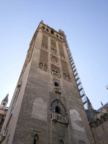 Vista desde abajo junto a la Giralda de Sevilla junto a Catedral de Sevilla, Fotografia realizada en despejado sin nubes, a contra luz y cielo azul - Fotografia realizada el 31 de Octubre del 2017, Sevilla, Endülüs, Espana, Europa