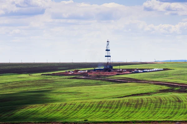 Drilling rig among green fields, a top view — Stock Photo, Image