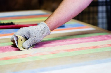 Marangoz zımpara bezi ile ahşap bir masa yüzeyine davranır