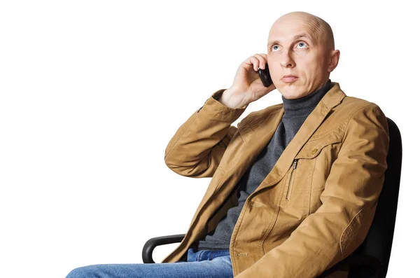 Man in het gele jas eist op mobiele telefoon zittend in een stoel van het Bureau — Stockfoto