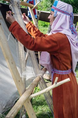 Kadın Ortaçağ kostümlü bir eski el dokuma tezgahı üzerinde çalışıyor