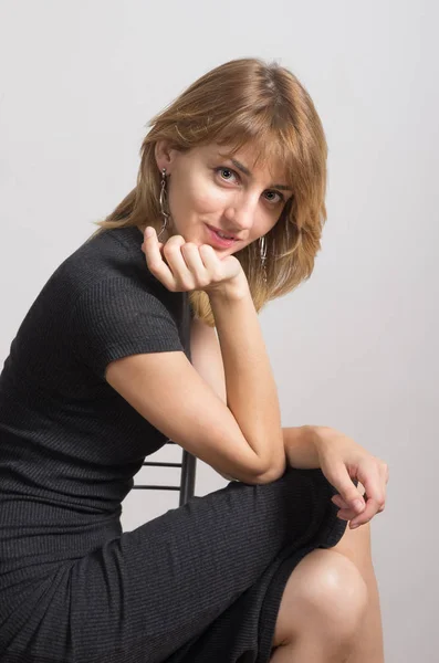 Portrait d'une fille en robe noire assise sur une chaise — Photo