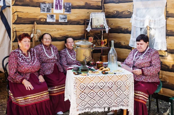Women in Russian folk costumes sit at a table with a samovar — Stock Photo, Image