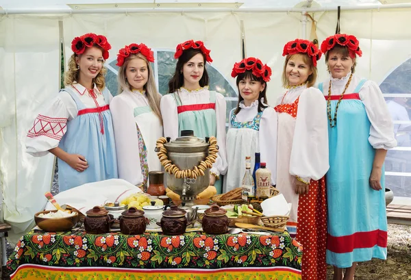 Women in national clothes, standing at a table with a samovar — Stock Photo, Image