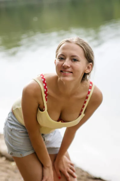 Mädchen in kurzen Hosen und T-Shirt posiert am Ufer des Sees — Stockfoto