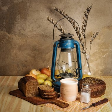 Bardak süt, ekmek, gazyağı fener, sebze ve tuz masanın üzerinde. Rustik tarzı natürmort