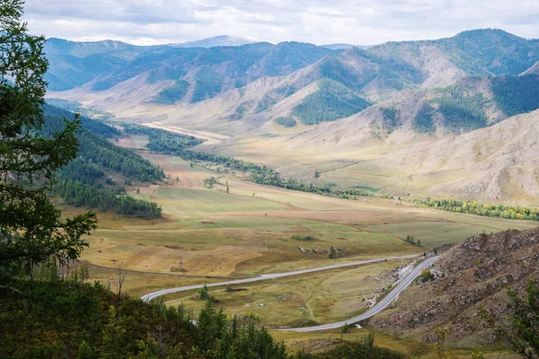 The valley of the Maly Ilgumen river, the old route of the Chuysky tract, the snow-capped peak of Mount Akkem on the horizon. View from the Chike-Taman pass, mountain Altai, Russia