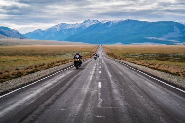 Şafak vakti Chuysky yolu boyunca giden motosiklet sütunu. Otoyolu olan bir manzara. Rusya, Altai Dağı