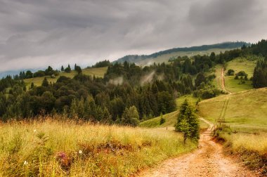 Dağ çayır dramatik gökyüzü ile yol. Kırsal dağlar manzara