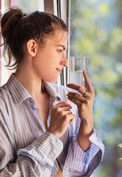 Hermosa joven bebe agua en la mañana cerca de la ventana — Foto de Stock