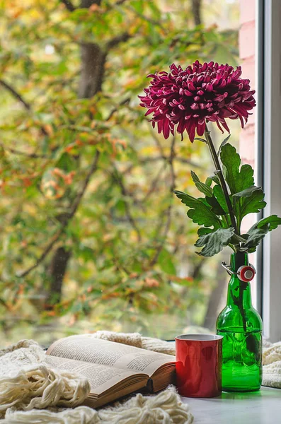 Sonbahar natürmort çiçek vazoda, kitap, çay veya kahve açmak ve halı örme