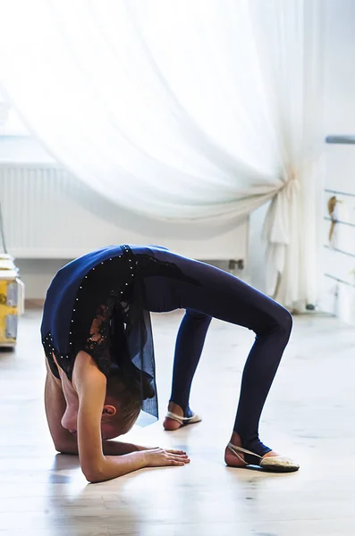 Young acrobatic girl shows the flexibility of the body at the gymnastic studio