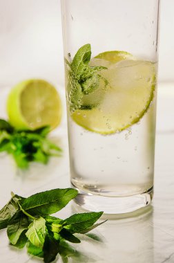 Soğuk taze su kabarcıkları, kireç, buz ve cam beyaz zemin üzerine nane ile. Sağlıklı yaşam konsepti