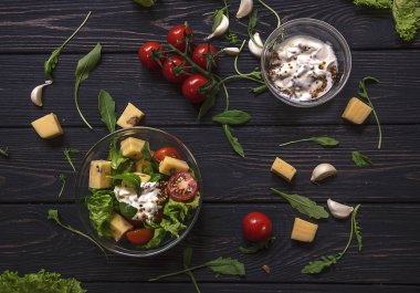 Kiraz domates, peynir, roka ve Mısır salata siyah ahşap zemin üzerine hardallı krem soslu salata. Rustik tarzı, üstten görünüm