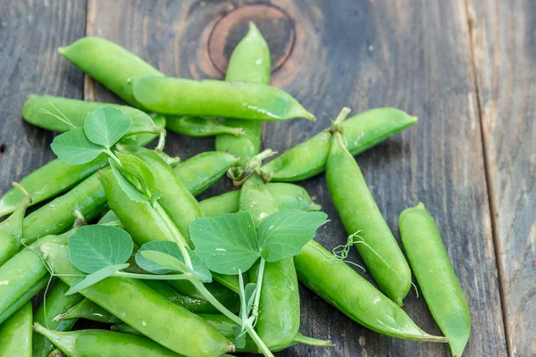 Doperwten en peulen van erwten op een donkere achtergrond. Begrip van gezond eten. — Stockfoto