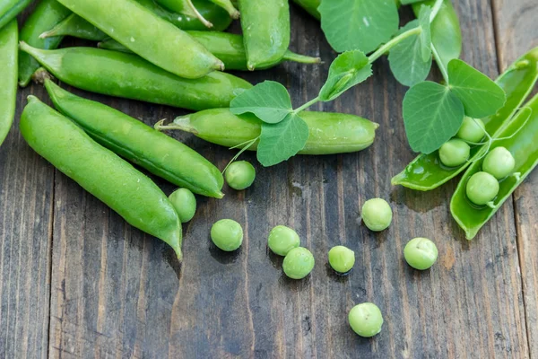 Guisantes y vainas de guisantes sobre un fondo oscuro. Concepto de alimentación saludable . — Foto de Stock