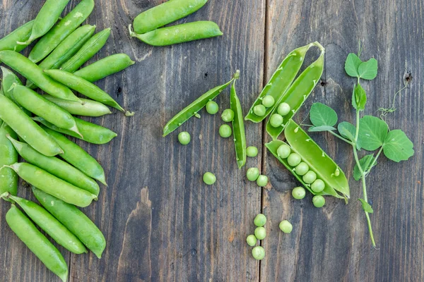 Guisantes y vainas de guisantes sobre un fondo oscuro. Concepto de alimentación saludable . — Foto de Stock