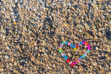 Cam çakıl deniz kıyısında parlak renkli kalp
