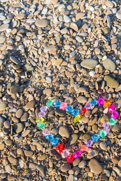 Coração brilhantemente colorido de seixos de vidro na costa do mar — Fotografia de Stock