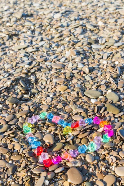 Brightly colored heart of glass pebbles on the sea shore — Stock Photo, Image