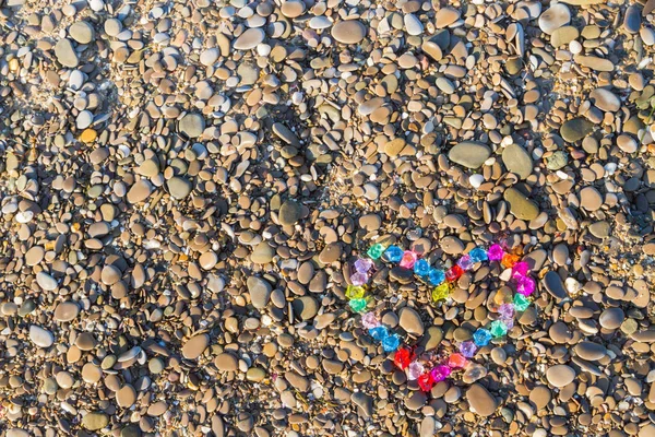 Cam çakıl deniz kıyısında parlak renkli kalp