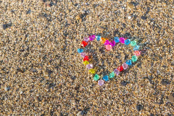 Brightly colored heart of glass pebbles on the sea shore — Stock Photo, Image