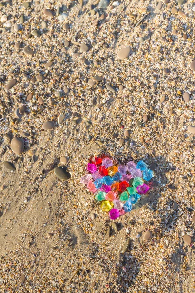 Brightly colored heart of glass pebbles on the sea shore — Stock Photo, Image