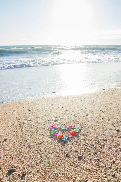 Coração brilhantemente colorido de seixos de vidro na costa do mar — Fotografia de Stock