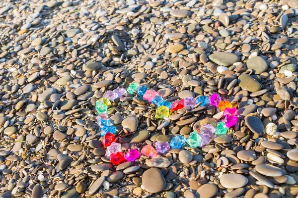 Brightly colored heart of glass pebbles on the sea shore — Stock Photo, Image