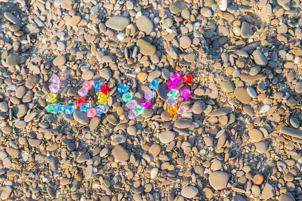 The inscription love of colored glass stones on sea rocks — Stock Photo, Image