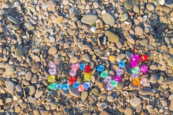 The inscription love of colored glass stones on sea rocks — Stock Photo, Image