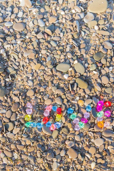 The inscription love of colored glass stones on sea rocks — Stock Photo, Image