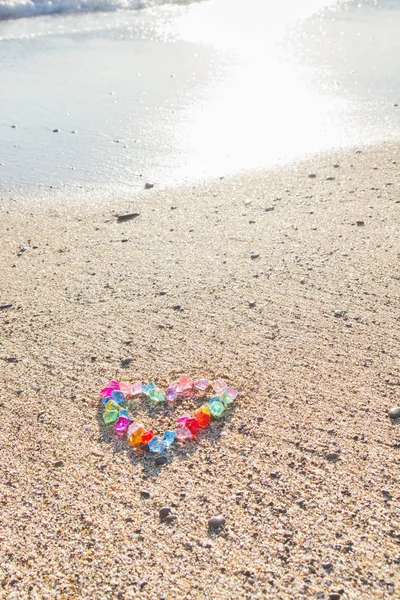 Ярко окрашенное сердце из стеклянной гальки на берегу моря — стоковое фото