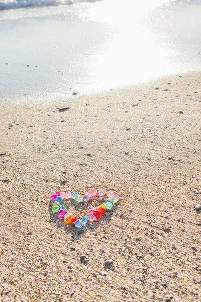 Cuore dai colori vivaci di ciottoli di vetro sulla riva del mare — Foto Stock