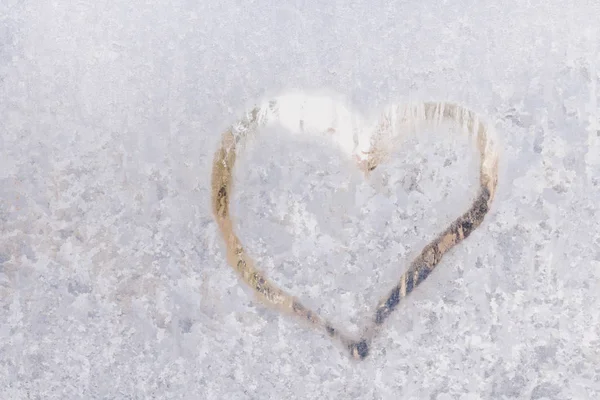 Heart on a frosty winter in the frozen patterns of ice window — Stock Photo, Image