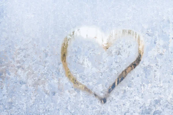 Heart on a frosty winter in the frozen patterns of ice window — Stock Photo, Image