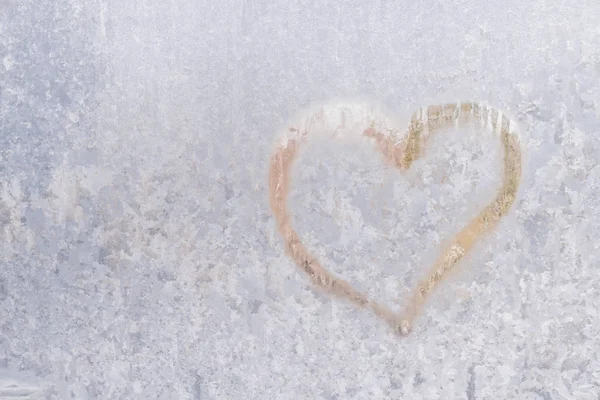Heart on a frosty winter in the frozen patterns of ice window — Stock Photo, Image