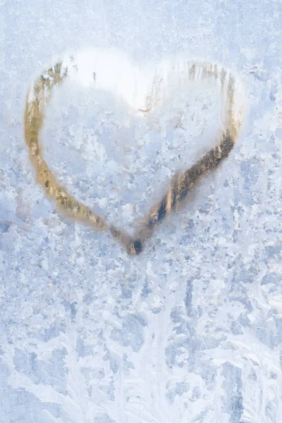 Coração em um inverno gelado nos padrões congelados da janela de gelo — Fotografia de Stock