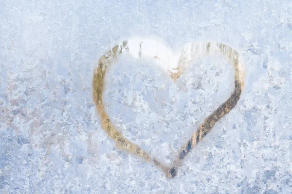 Coração em um inverno gelado nos padrões congelados da janela de gelo — Fotografia de Stock