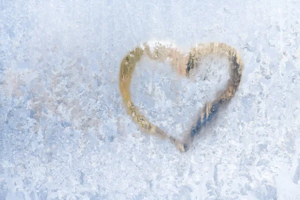 Coração em um inverno gelado nos padrões congelados da janela de gelo — Fotografia de Stock