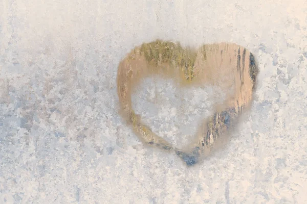 Coração em um inverno gelado nos padrões congelados da janela de gelo — Fotografia de Stock