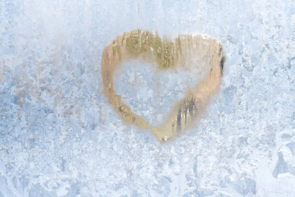 Coração em um inverno gelado nos padrões congelados da janela de gelo — Fotografia de Stock