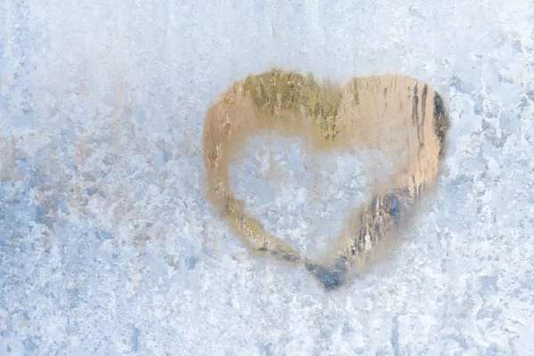 Coração em um inverno gelado nos padrões congelados da janela de gelo — Fotografia de Stock