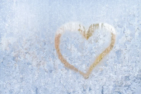 Heart on a frosty winter in the frozen patterns of ice window Stock Picture