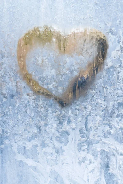 Heart on a frosty winter in the frozen patterns of ice window Stock Photo