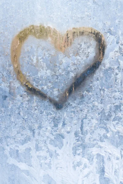 Heart on a frosty winter in the frozen patterns of ice window Stock Picture