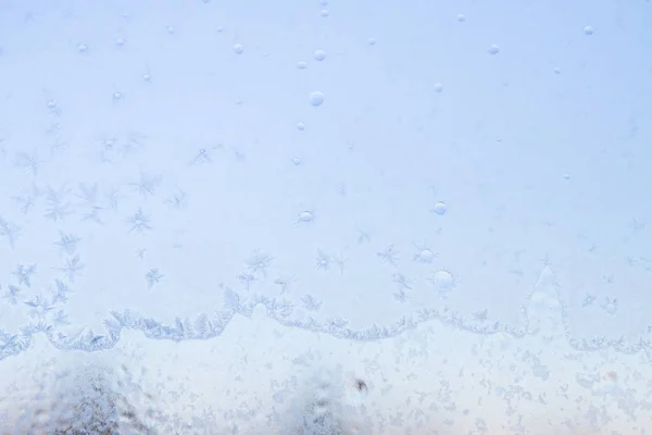 Frostige Wintermuster auf dem gefrorenen Eisfenster — Stockfoto