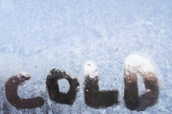 A inscrição é fria em uma janela congelada com padrões — Fotografia de Stock