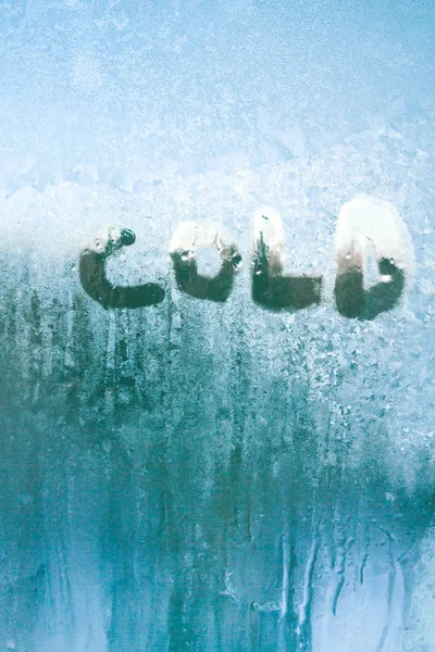 A inscrição é fria em uma janela congelada com padrões — Fotografia de Stock