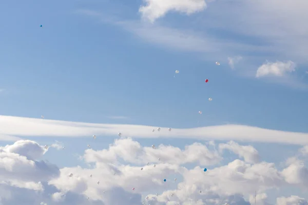 Colorful balloons fly in the blue spring sky with white clouds — Stock Photo, Image
